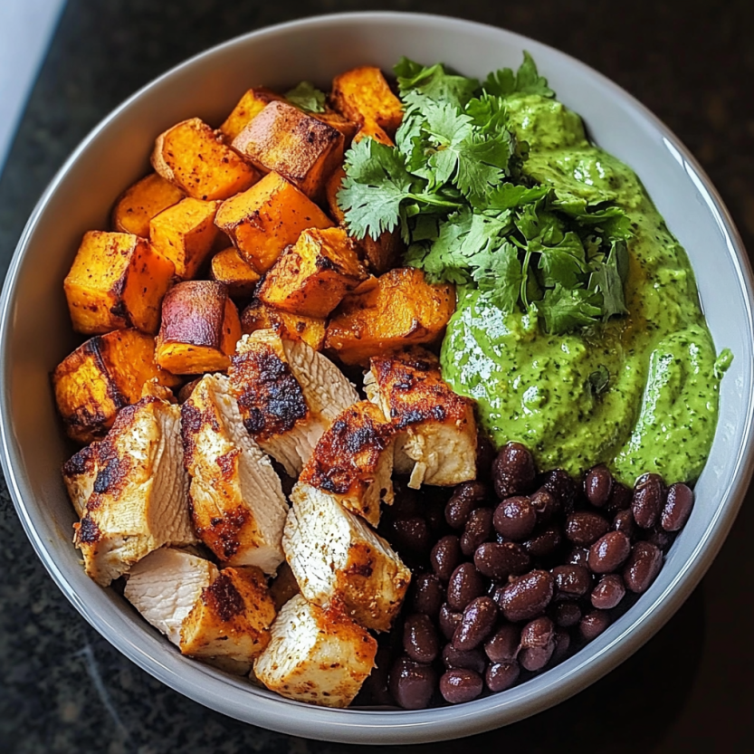 Un bol rempli de chips de poulet grillé, de haricots noirs, de patates douces et de coriandre fraîche.