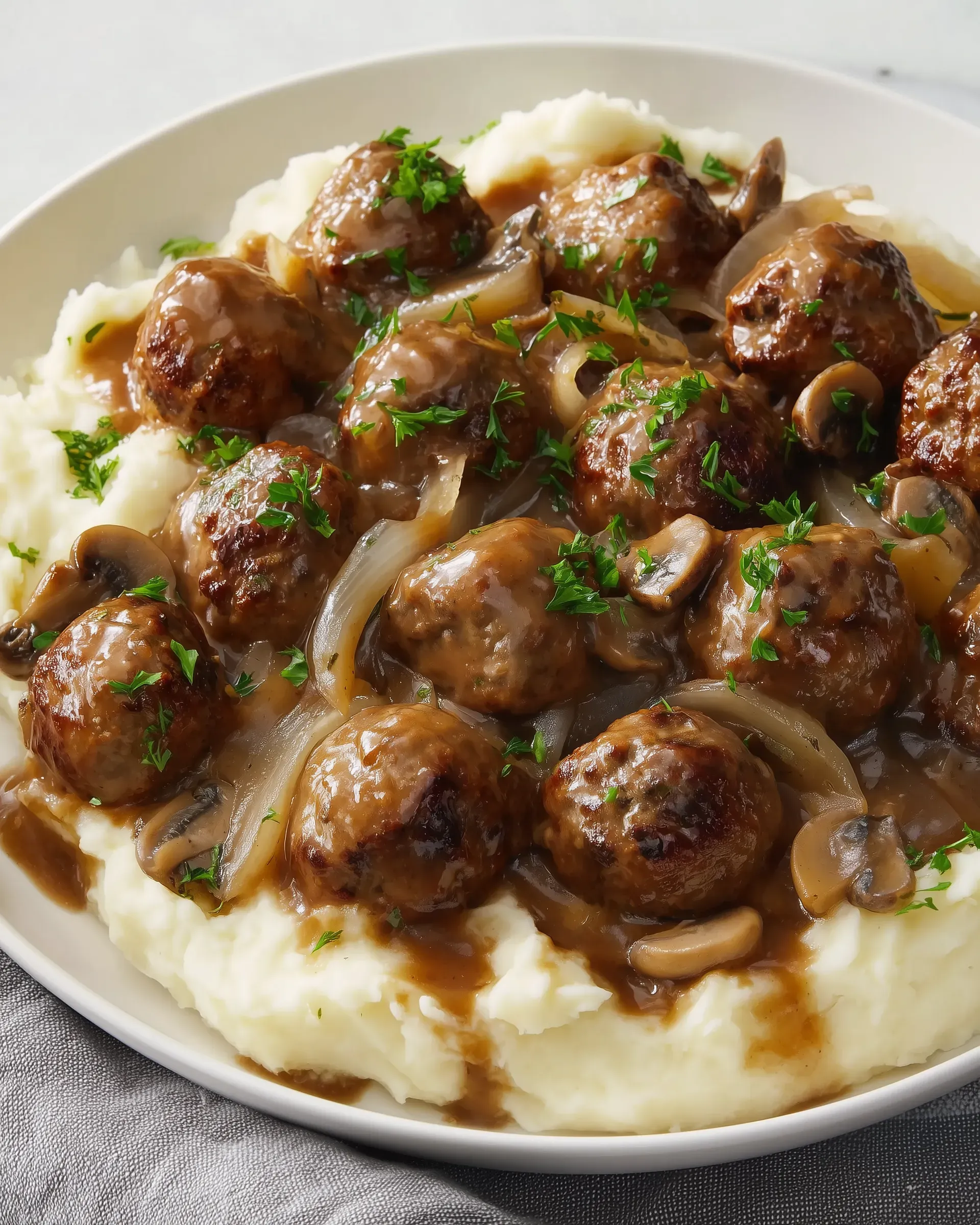 A plate of meatballs with mushrooms and onions.