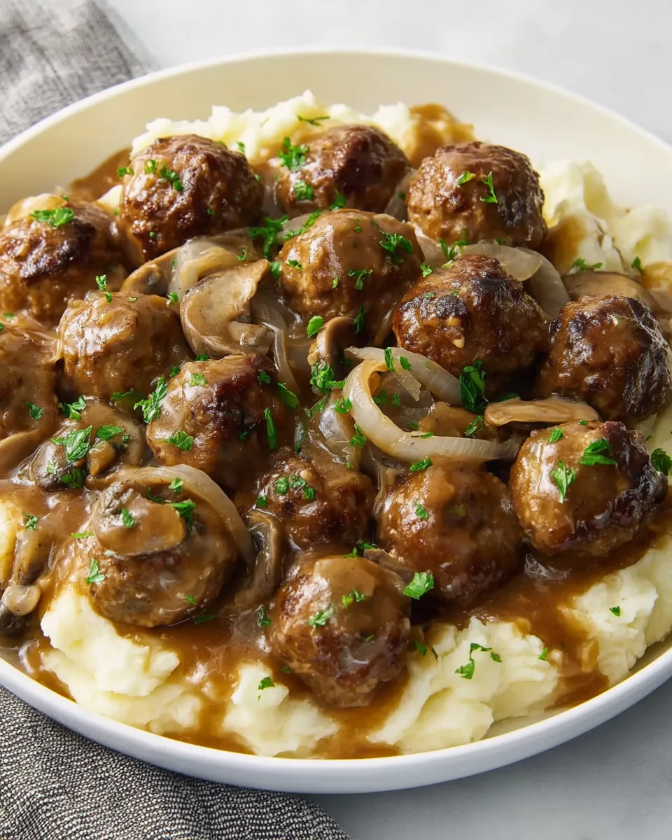 A plate of meatballs with mushrooms and onions.