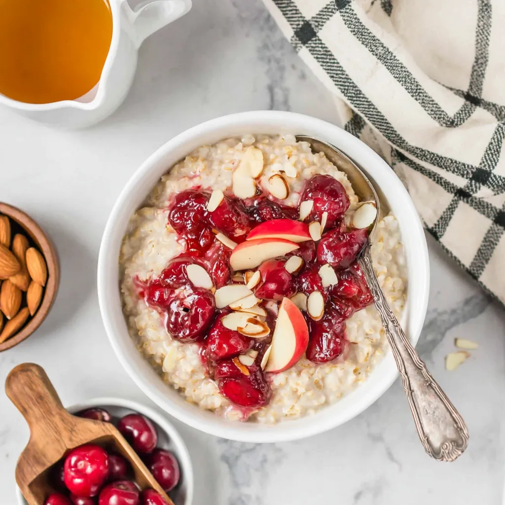 A bowl of oatmeal with fruit on top.