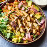 A bowl loaded with veggies and chicken pieces.