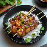Rice and skewered chicken on a plate, ready to eat.