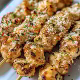 Chicken skewers loaded with parmesan and sprinkled parsley.
