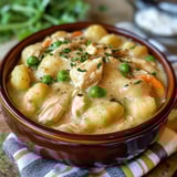 A bowl loaded with chicken, veggies, and fluffy gnocchi in creamy broth.