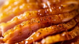A glazed ham slice up close, golden and juicy.