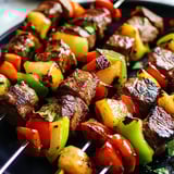 Platter loaded with steak and pineapple skewers with bright peppers.
